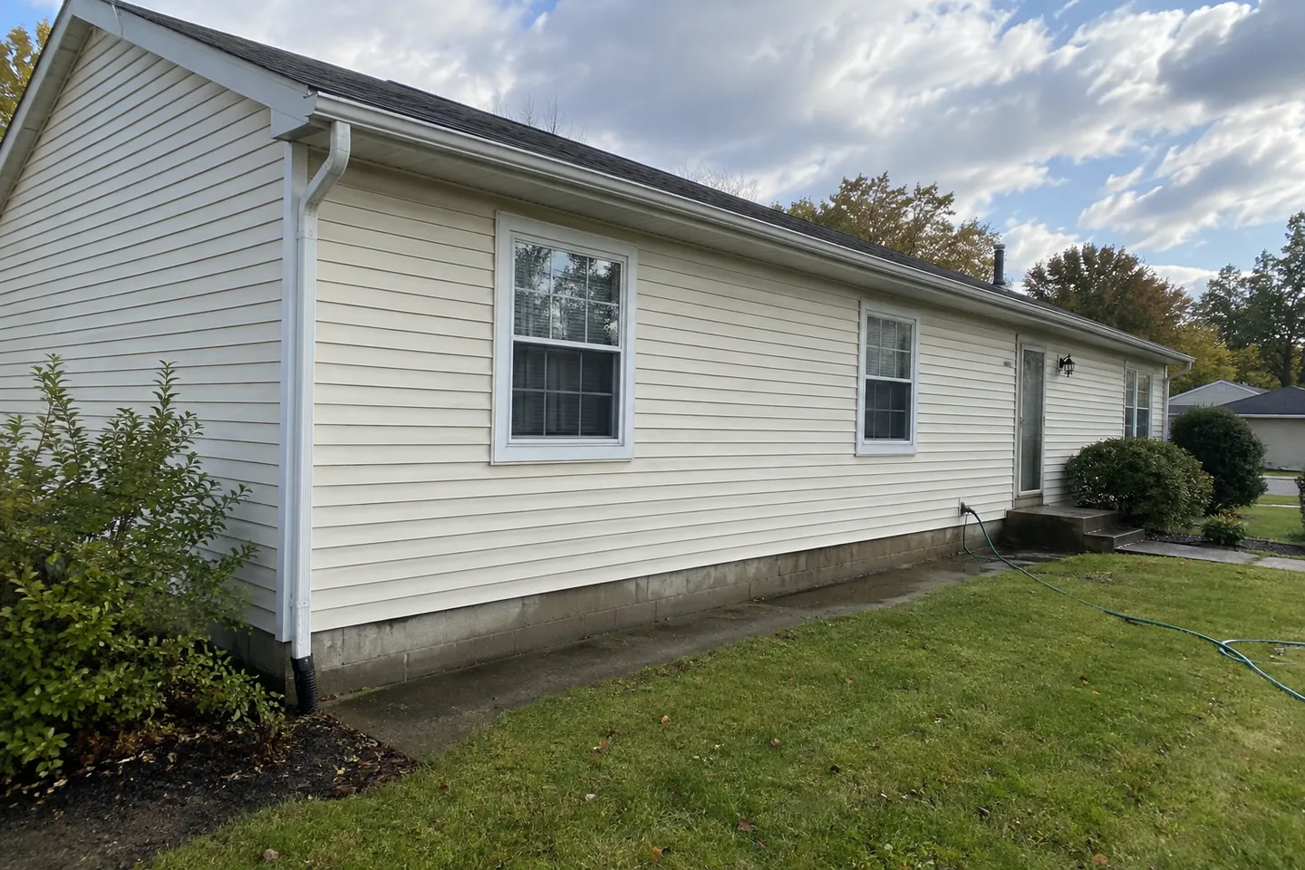 Cream vinyl siding and white-framed windows on a modest home